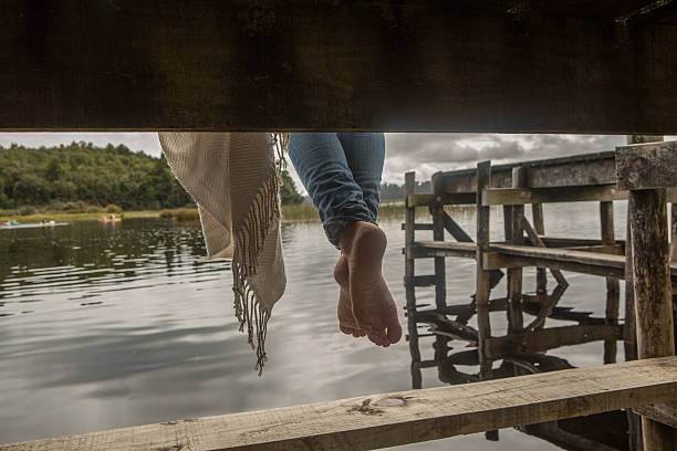 istock Woman's feet dangle from lake pier 545432602