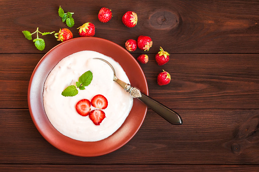 Healthy yogurt with strawberry on wooden background. Rustic food. Flat lay, top view