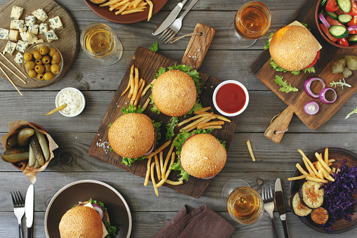 Different burgers with snacks and wine on the wooden table, top view. Outdoors food Concept