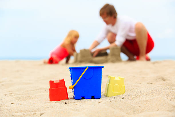 istock father and little daughter play with sand at beach 545439408