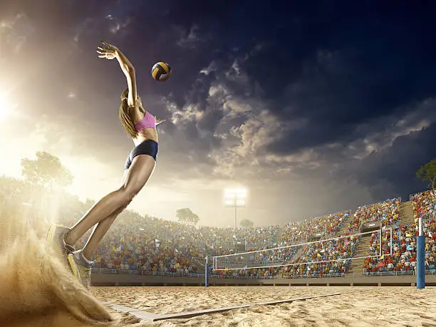 Beautiful female volleyball player performs an emotional game moment on the sand volleyball stadium with bleachers full of people. She is wearing an unbranded sports cloth.