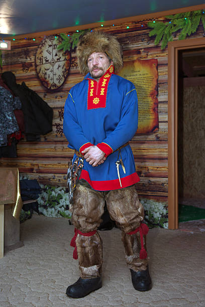 Millennial non-binary person getting dress in a Scottish kilt for wedding. They are body positive with short hair and a beard. Vertical waist up indoors shot. This was taken in Quebec, Canada.
