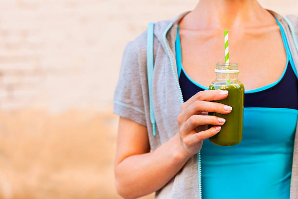 Woman drinking vegetable smoothie after fitness running workout Woman drinking vegetable smoothie after fitness running workout on summer day. Fitness and healthy lifestyle concept aloe juice stock pictures, royalty-free photos & images