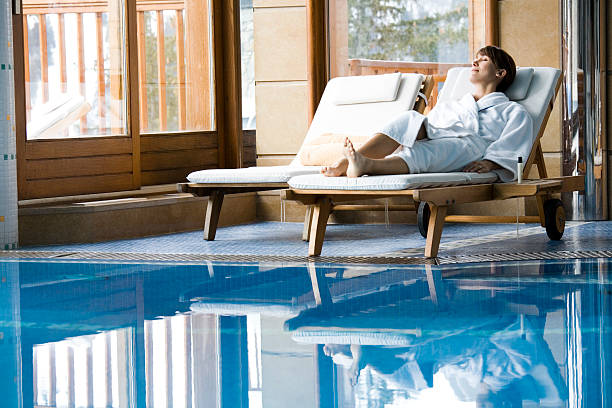 woman on a sun lounger resting by an indoor pool