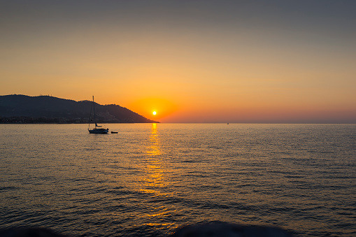 Sunrise over sea with a sail boat. Diano Marina. Liguria. Italy.