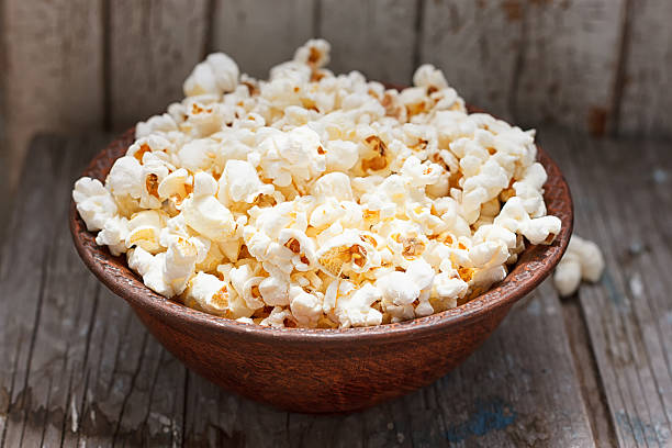 istock Fresh popcorn in bowl on white wooden table 545456554