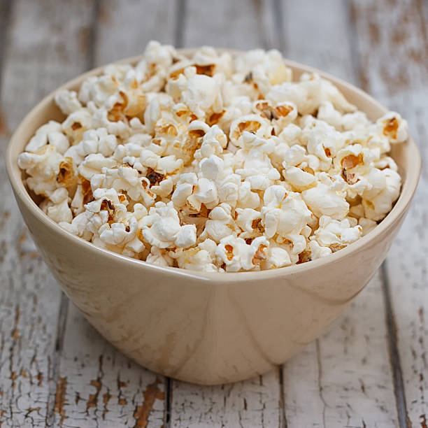 istock Fresh popcorn in bowl on white wooden table 545457158