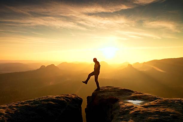 istock Man in black jumping between peaks. Dreamy daybreak 545460062