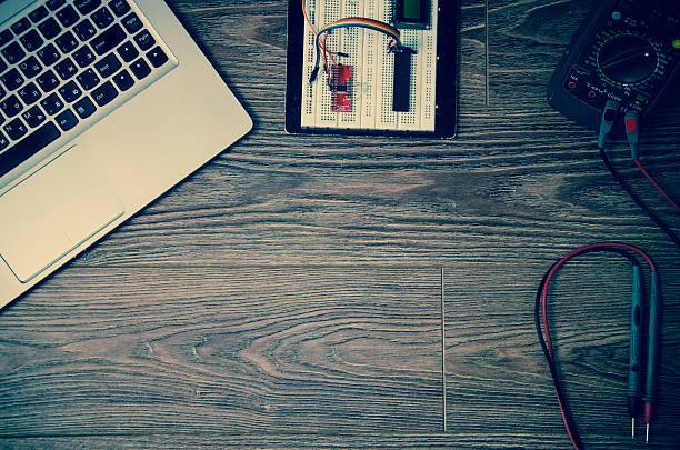 istock laptop, multimeter, prototyping board on a wooden table 545463140