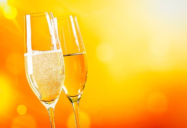 istock champagne flutes with golden bubbles on golden light background 545466044