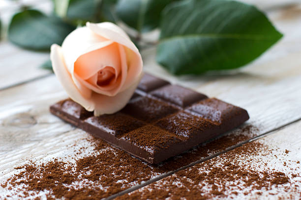 rose, coffee and slices of chocolate on the wooden table stock photo