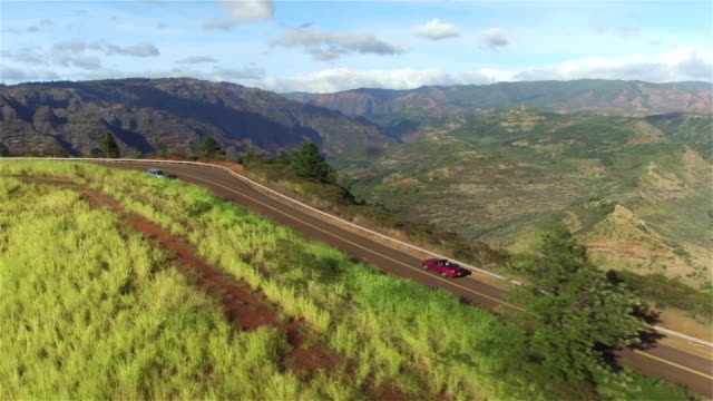 AERIAL: Red convertible driving on winding road on the edge of grand canyon