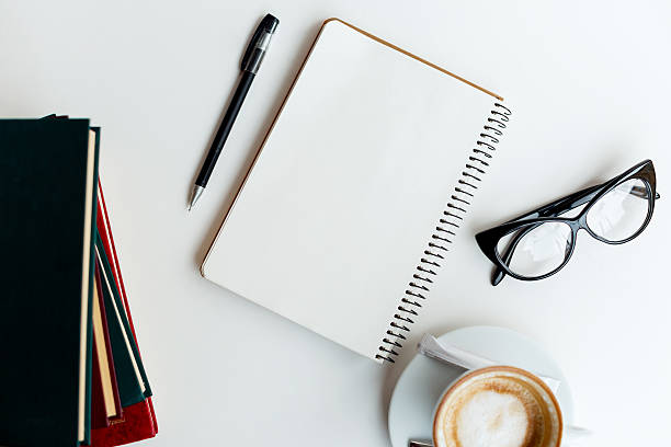istock Clear notebook, cup of coffee, glasses and books on table 545548980