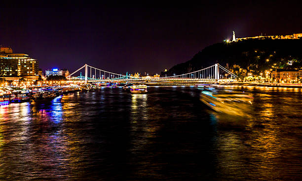 Cruise Boats Abstract Danube River Night Budapest Hungary Cruise Boats Abstract Danube River Passing Under Chain Bridge Night Budapest Hungary.  Elizabeth Bridge in the distance budapest danube river cruise hungary stock pictures, royalty-free photos & images