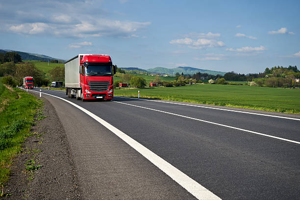 istock Red trucks arriving on the road winding through the fields. 545553404