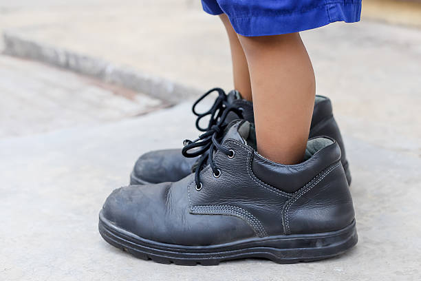 istock child's feet in large black shoes 545557752