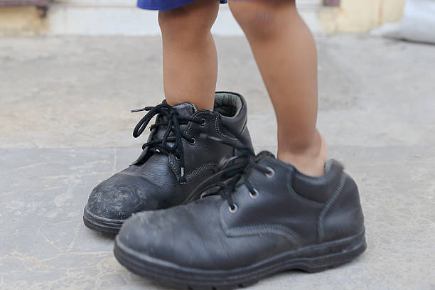 istock child's feet in large black shoes 545558444