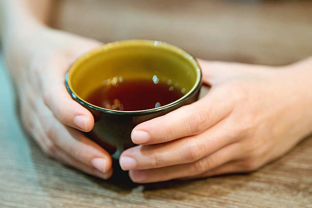 les mains féminines tenant une tasse de thé - tea green tea jasmine chinese tea photos et images de collection