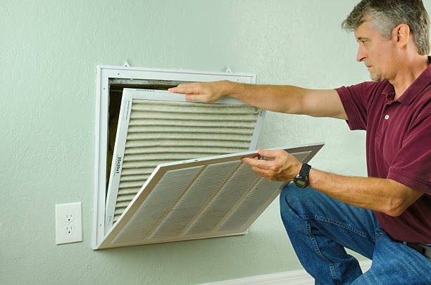 Home owner replacing air filter on air conditioner Professional repair service man or diy home owner removing a dirty air filter on a house air conditioner so he can replace it with a new clean one. filtration stock pictures, royalty-free photos & images