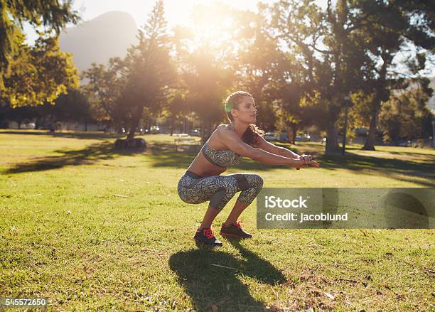 Fit Young Woman Doing Squatting In Park Stock Photo - Download Image Now - Exercising, Outdoors, Squatting Position