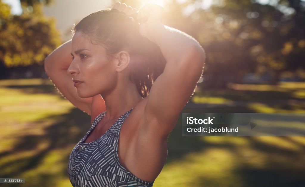 Tough young woman getting ready for training. Closeup shot of fit female athlete tying hair before her workout. Tough young woman getting ready for training. Exercising Stock Photo