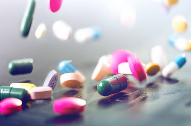 lévitation des pilules sur fond noir - vitamin pill nutritional supplement capsule antioxidant photos et images de collection