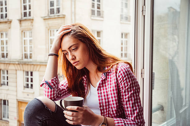 istock Depressed woman sitting at the window 545582934