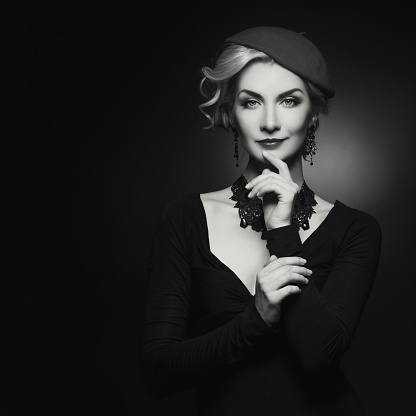 Beautiful lady in beret. Beauty portrait. Film noir retro style. Over black background. Monochrome.