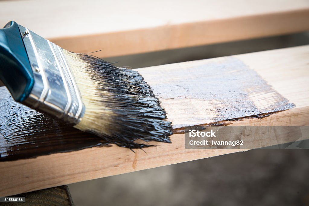 Varnishing natural wood with paint brush. Wood texture Varnishing natural wood with paint brush. Wood texture and paintbrush - housework background Brown Stock Photo