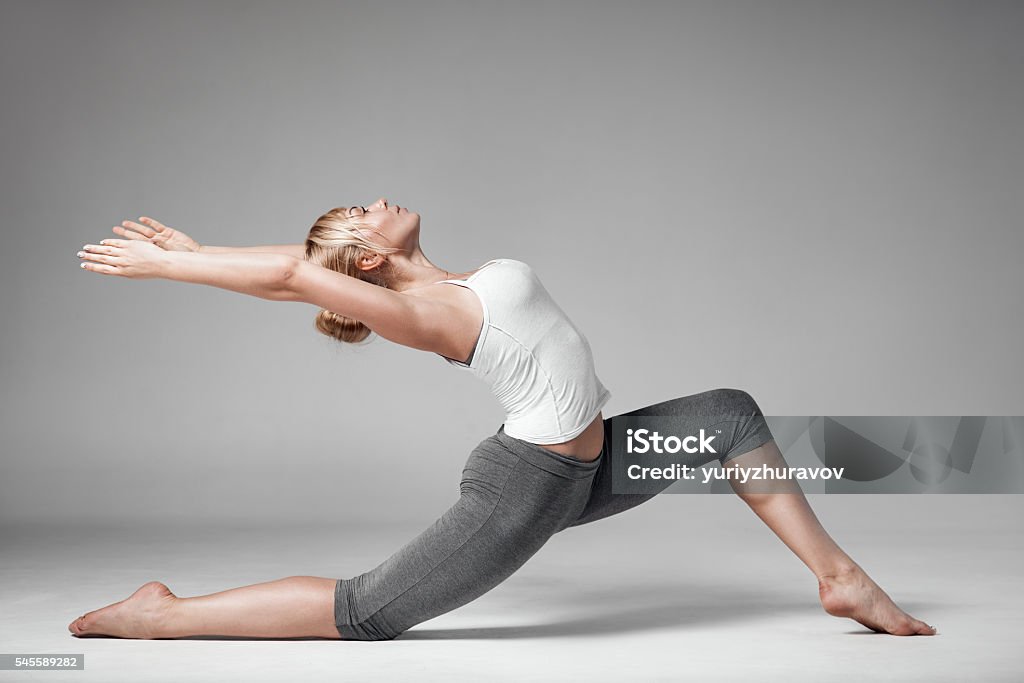 Full length of a young woman stretching body. Gray Background. Activity Stock Photo