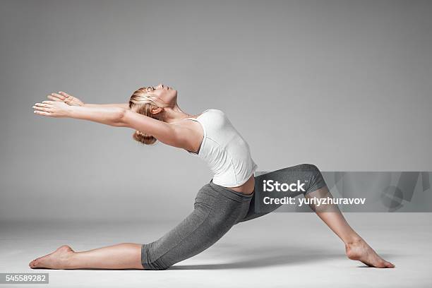 Full Length Of A Young Woman Stretching Body Gray Background Stock Photo - Download Image Now