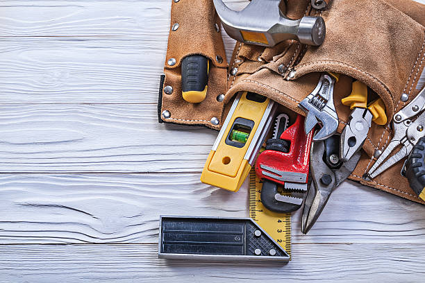istock Brown leather tool belt with building implements on wooden board 545592166