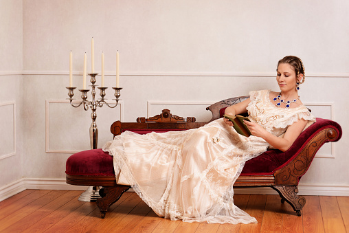 portrait of victorian woman reading book on fainting couch