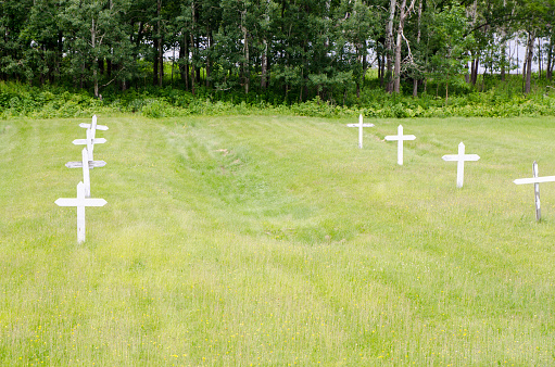 Mass grave showing row of cross with the recessed ground on each side during day of summer