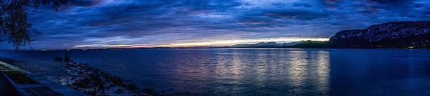 Night panorama of resort Garda Lake, Italian Alps (mount Monte Are) and city lights of Comune di Garda. Lake Garda, Bardolino, Italy. HDR photo. High-Resolution Panorama.