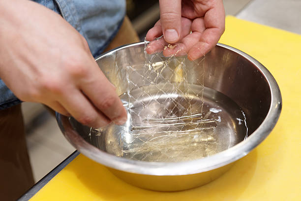 Chef is soaking gelatin sheets in water Chef is soaking gelatin sheets in cold water gelatin stock pictures, royalty-free photos & images