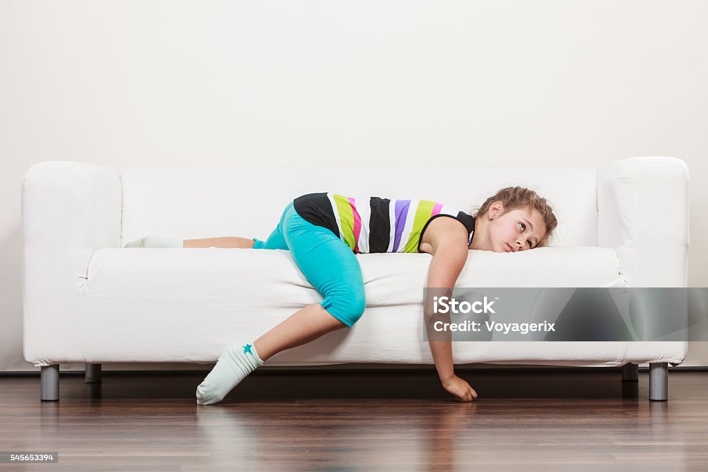 Tired exhausted lazy little girl kid lying on sofa Tired exhausted lazy little girl lying on sofa at home. Sleepy kid resting relaxing on couch. Child Stock Photo