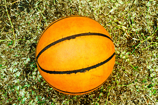 Worn ball basketball on dry grass