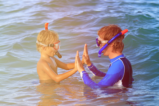 happy father and little son snorkeling on beach