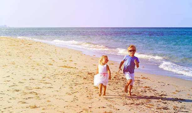 istock little boy and girl running at beach 545655770