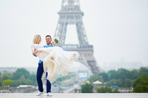 Just married couple near the Eiffel tower on their wedding day. Bride and groom in Paris, France