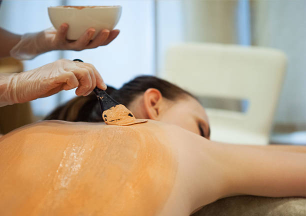 Beautiful relaxed woman having clay body mask