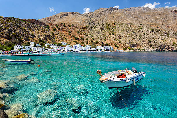 моторная лодка на чистой воде города лутро на острове крит - mountain sea house landscape стоковые фото и изображения