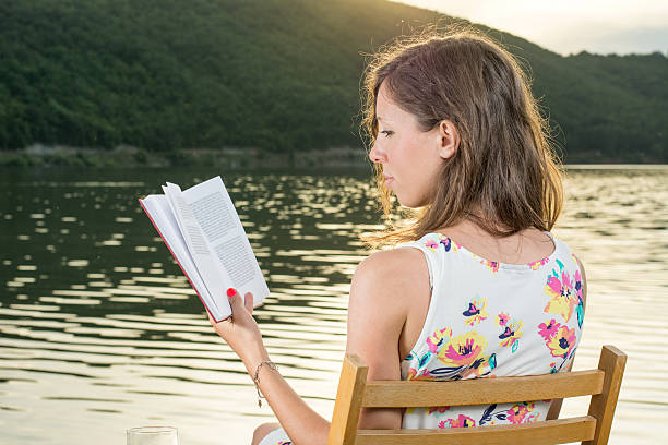 istock Woman reading a book by the lake 545665762