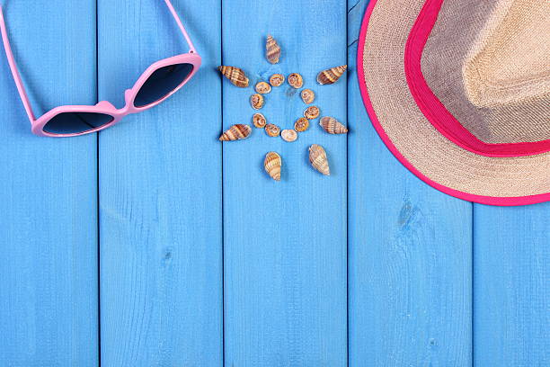 istock Seashells in shape of sun, sunglasses, straw hat on boards 545666242
