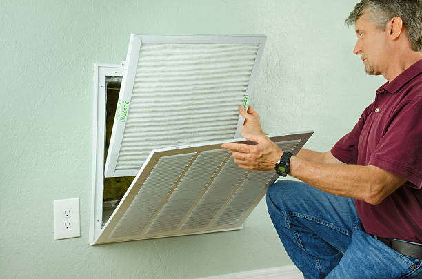Home owner putting new air filter on air conditioner stock photo