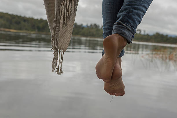 istock Woman's feet dangle from lake pier 545675378