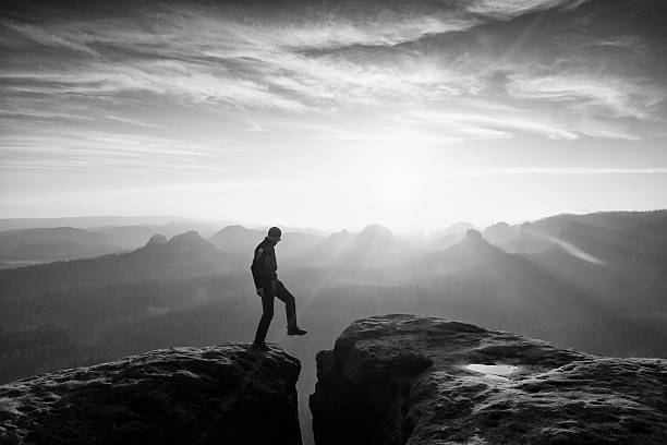 istock Hiker in black is jumping between mountains peaks. 545675384