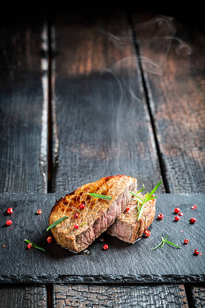 istock Hot grilled meat with fresh rosemary on black rock 545676216