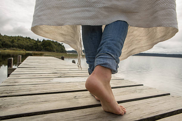 Close up on woman's feet standing on a jetty above the lake.